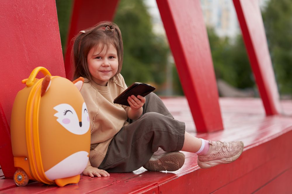 A little smiling girl with a smartphone in her hand.