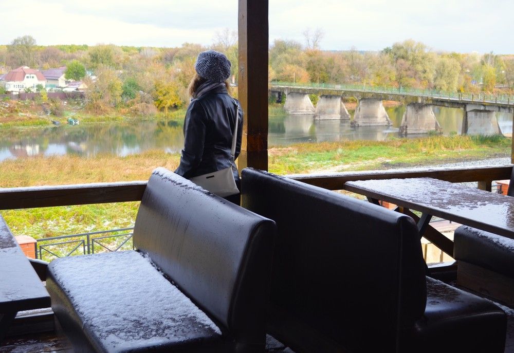 Девушка в кафе смотрит на природу.