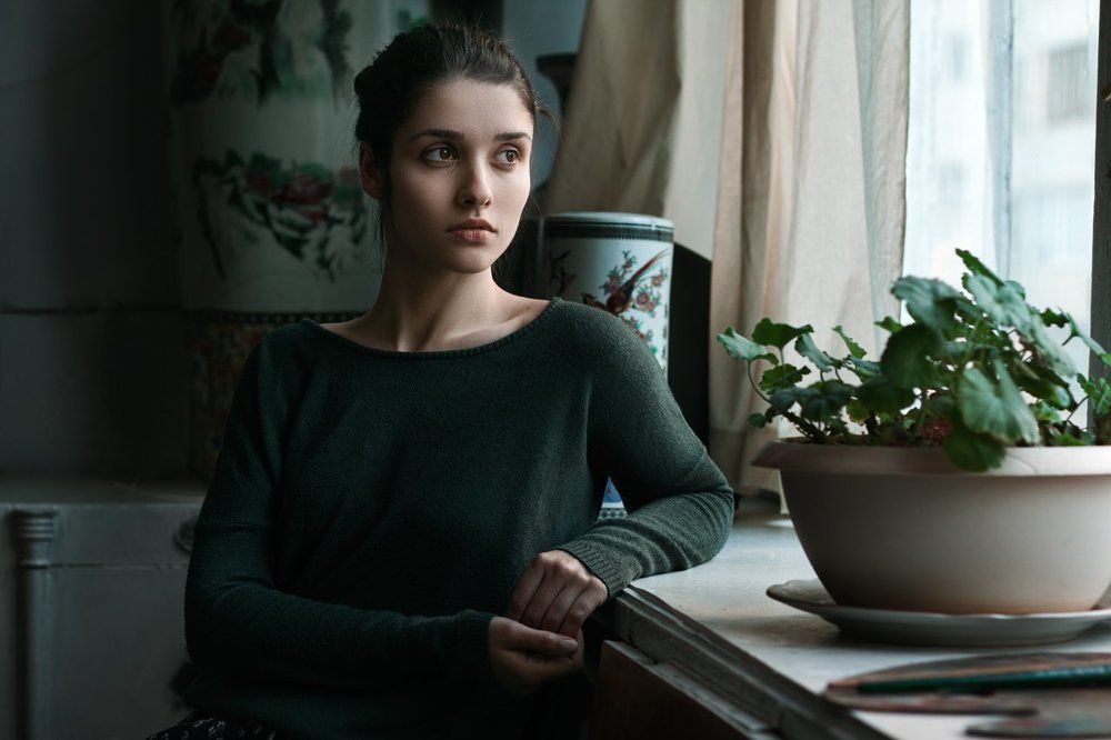 Одна у окна.