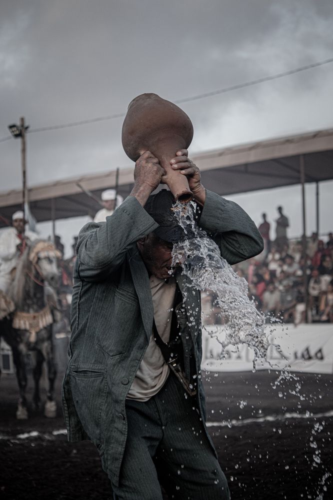 Unique Moment: A man pouring water from a clay bottle onto his hat after a unified cavalry charge.