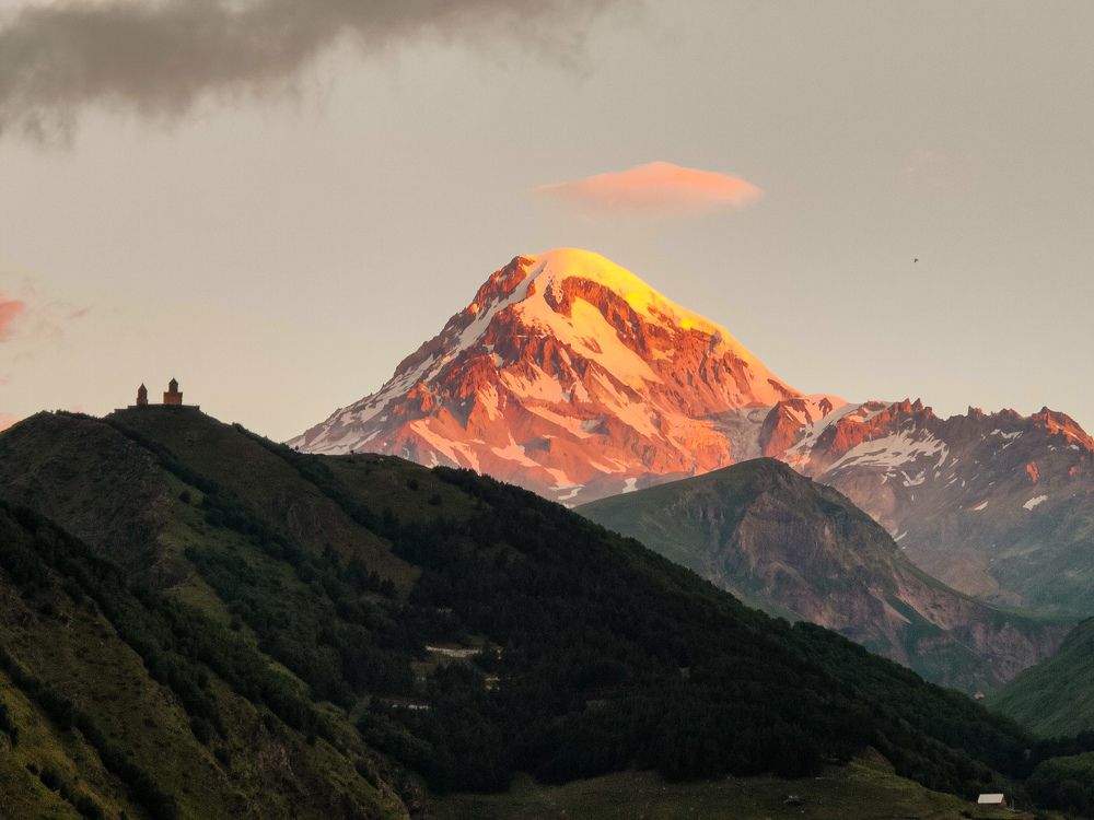 The sunset over the Mount Kazbek (5033 m) and Gergeti Trinity Holy church