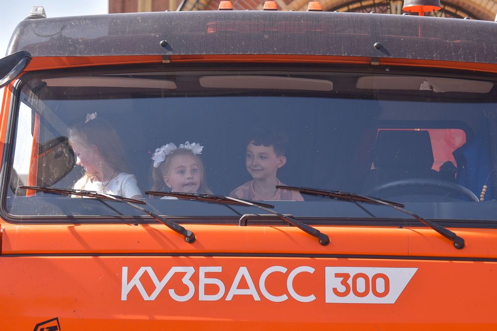 Первоклассники сидят в кабине КАМАЗа.