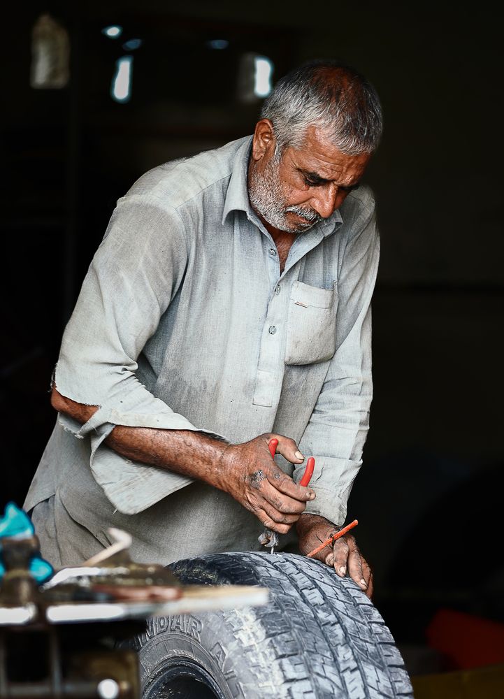 Dedicated Pakistani Mechanic Repairing a Car Tire
