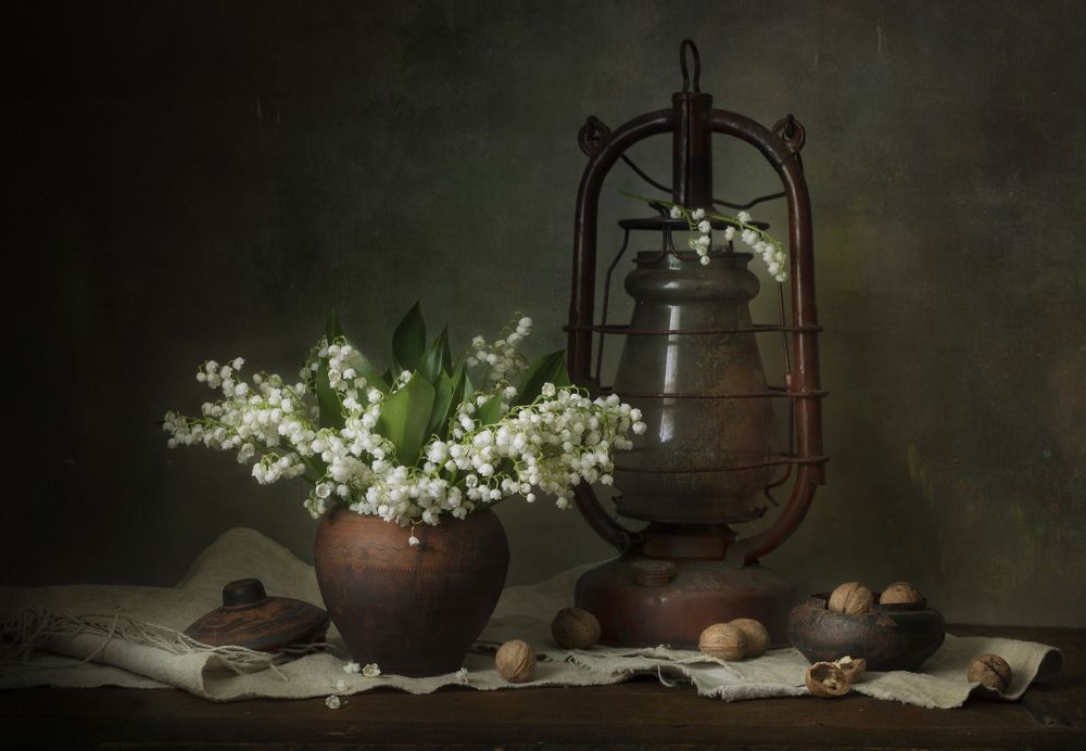 Still life with lilies of the valley and last year's nuts