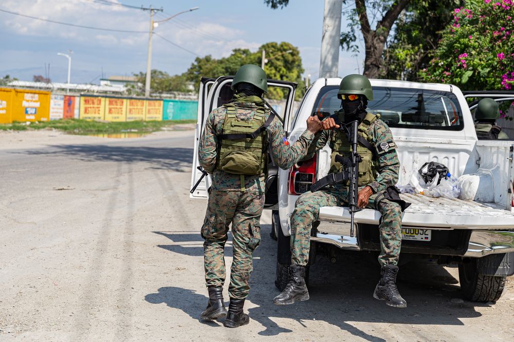 Soldiers make hand gestures as they guard the entrance to Port-au-Prince international airport.