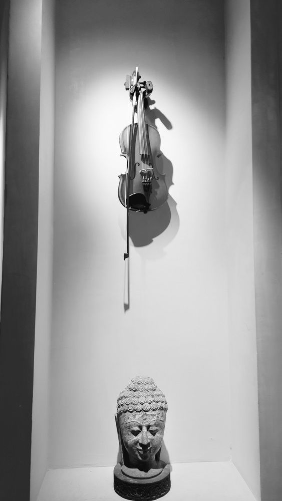 Violin and a sculpture of Gautam Buddha.