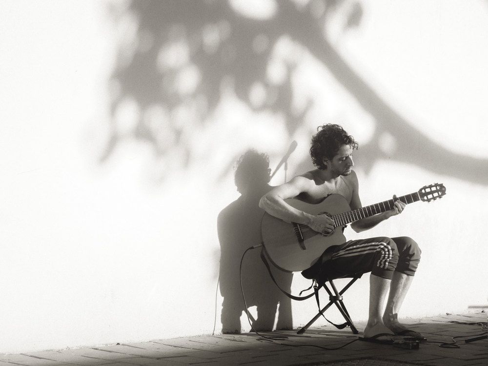 A musician is playing a waltz under a tree.