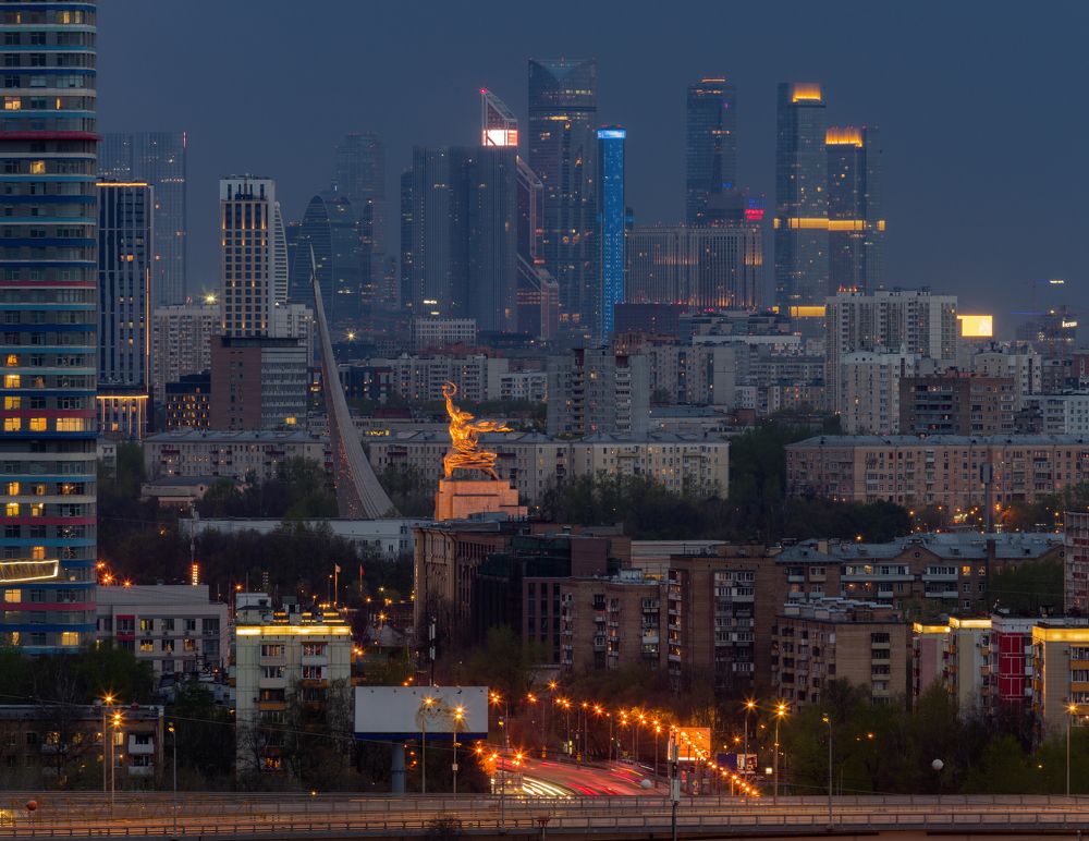 Рабочий и Колхозница на фоне сумеречной городской застройки