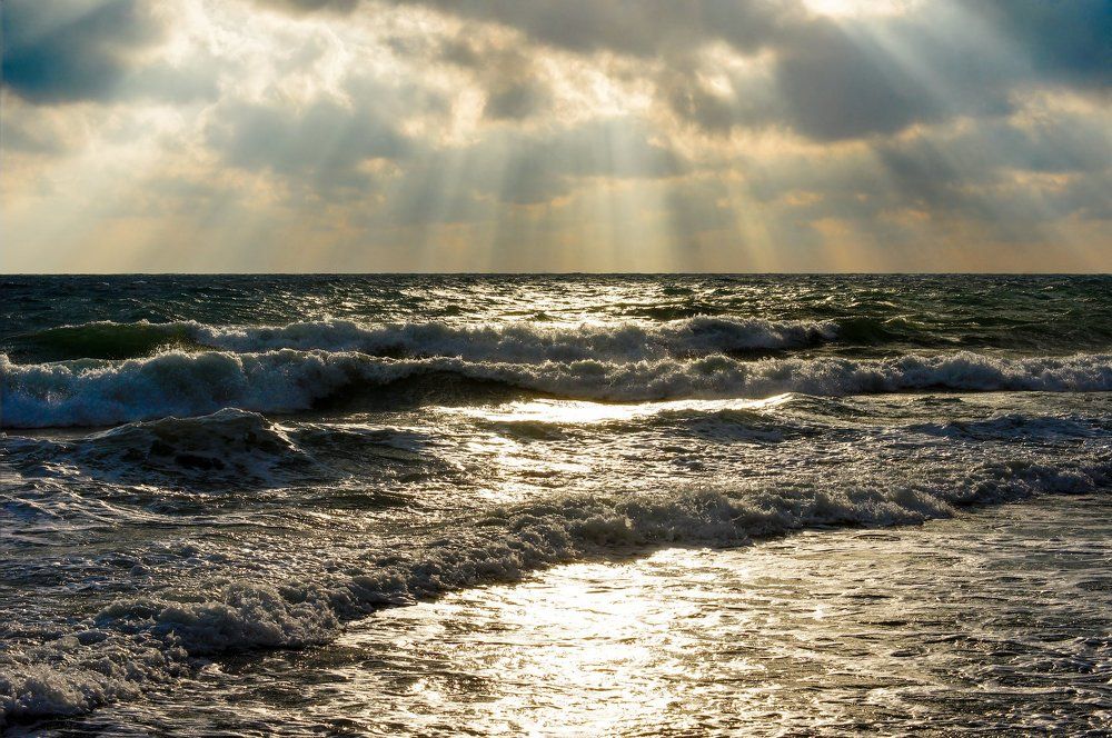 Лучи зимнего солнца, объявшие штормовое море.