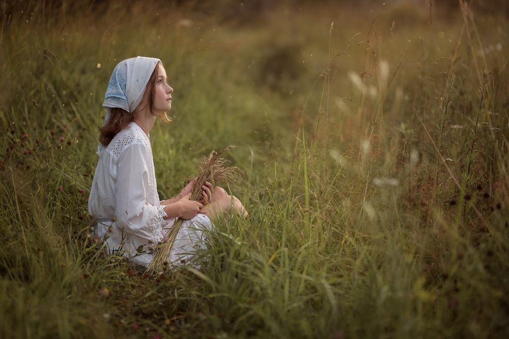 Девочка сидящая на траве.