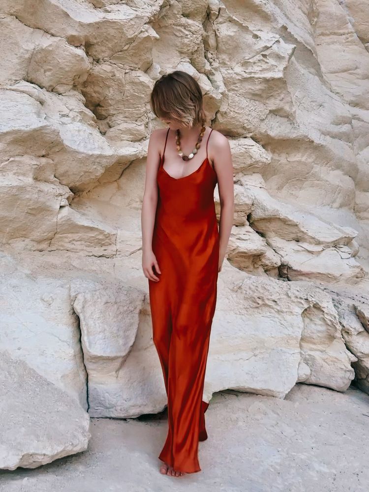 Девушка в красном шелке у скалы