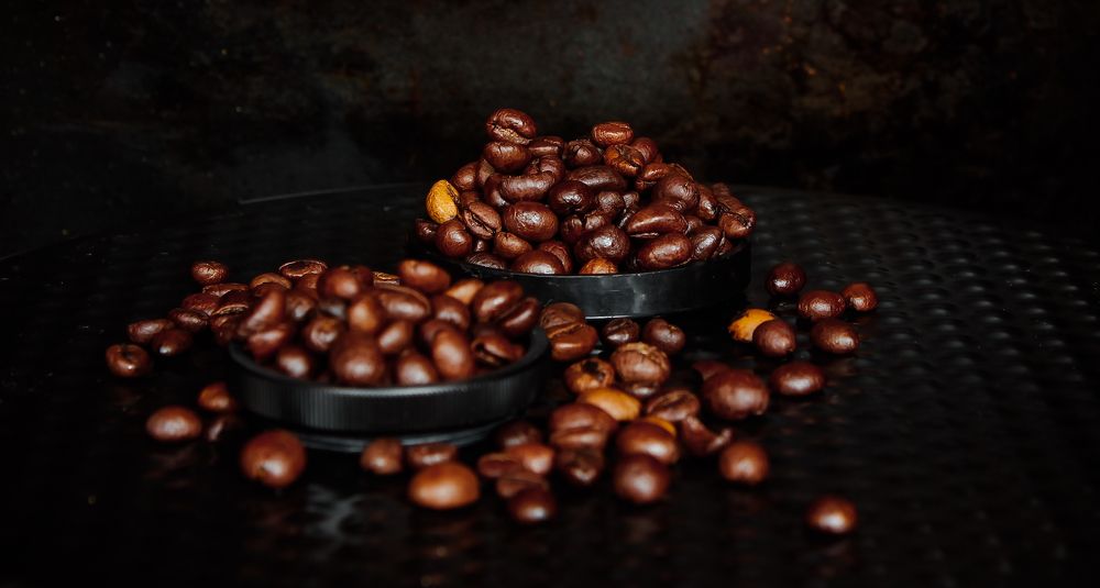 Two small handfuls of roasted coffee beans