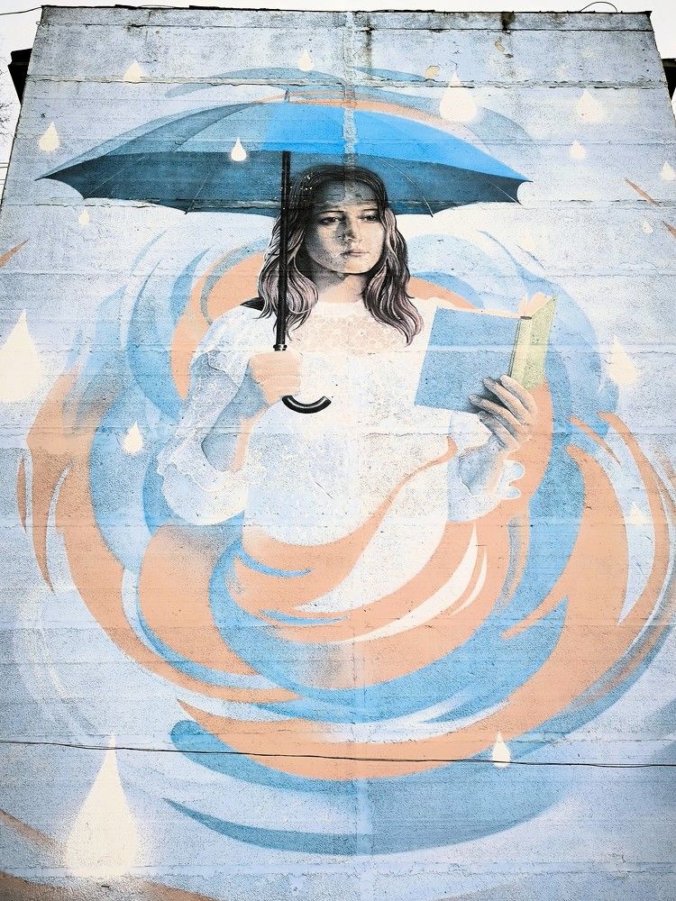 Огромное граффити в виде девушки под зонтом, читающей Пастернака