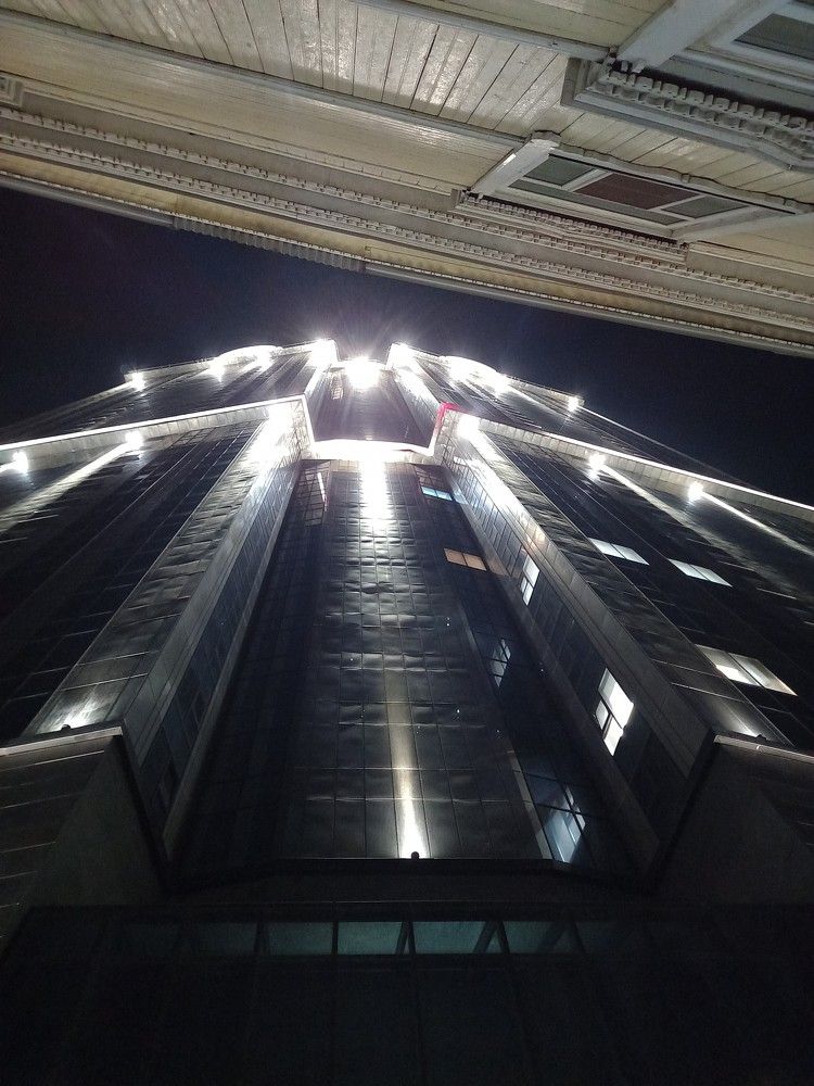 За небоскребом.