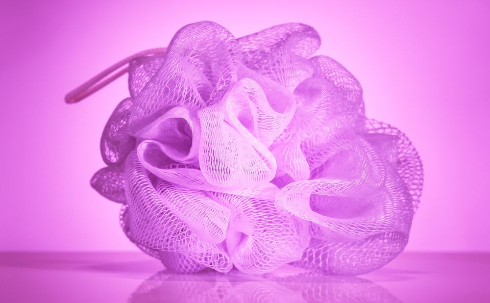 Pink and white nylon mesh washcloth on pink background