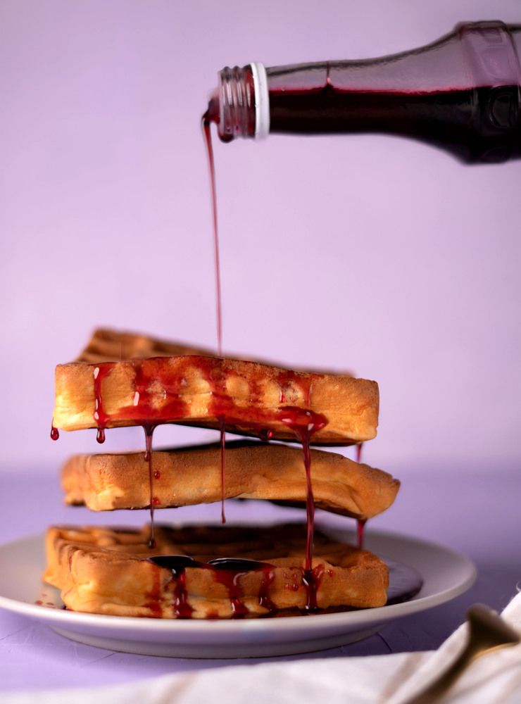photo Delicious golden waffle stack generously drenched with crimson syrup, creating a perfect delightful breakfast treat or dessert indulgence for food enthusiasts
