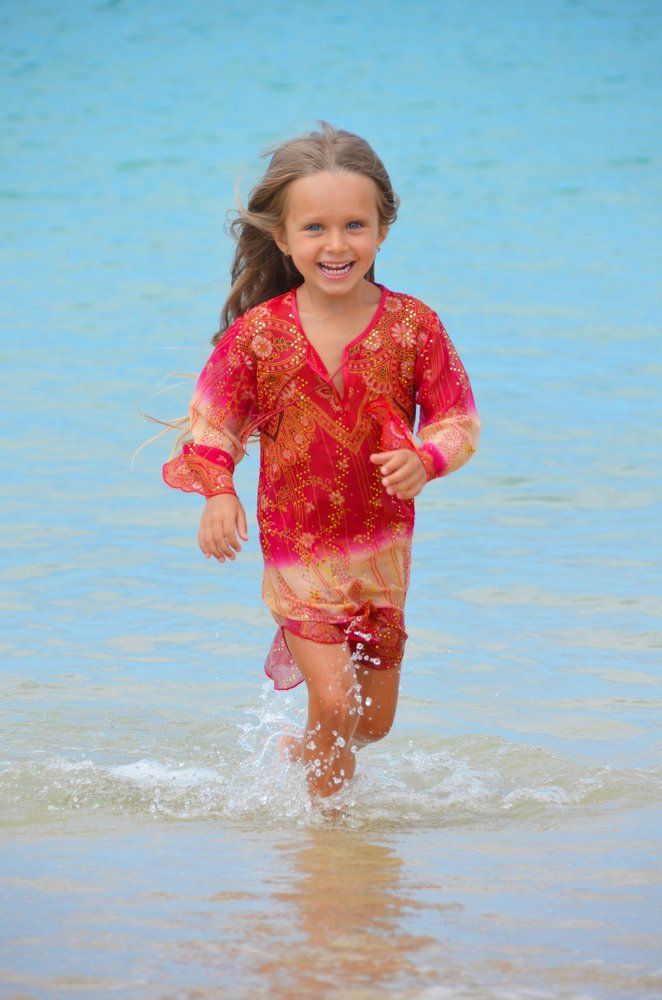 Beautiful young girl is running in the ocean