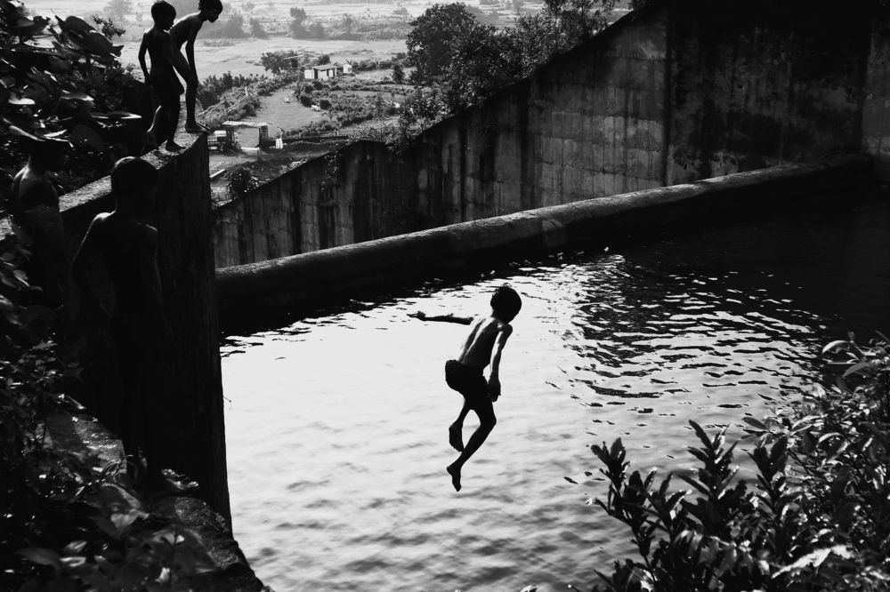 school children enjoying and diving into dam' s water.