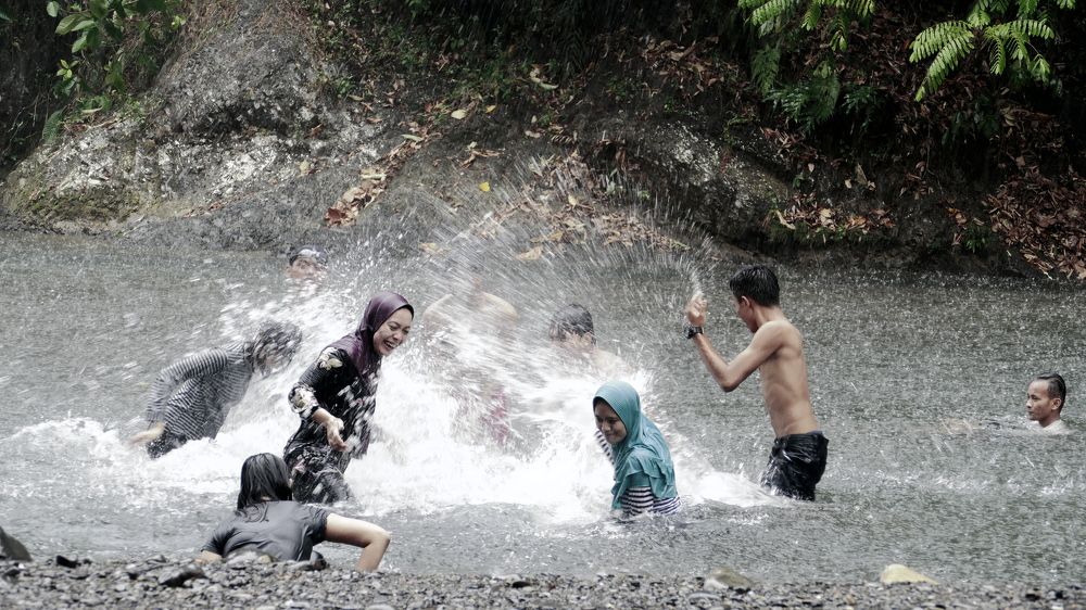Happy teenagers playing in the river