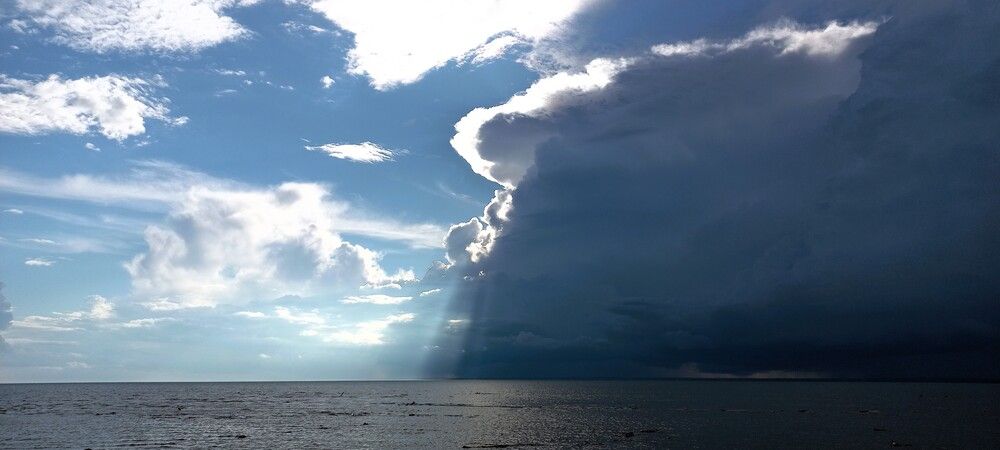 Heavy dark rain cloud over blue sea before rain