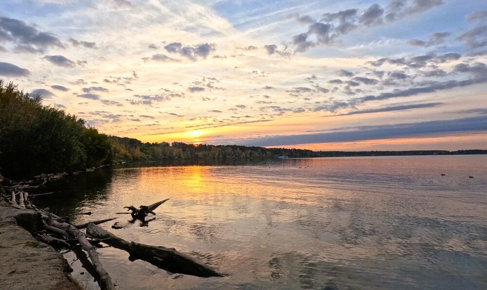 Закат над рекой, с деревьями на горизонте