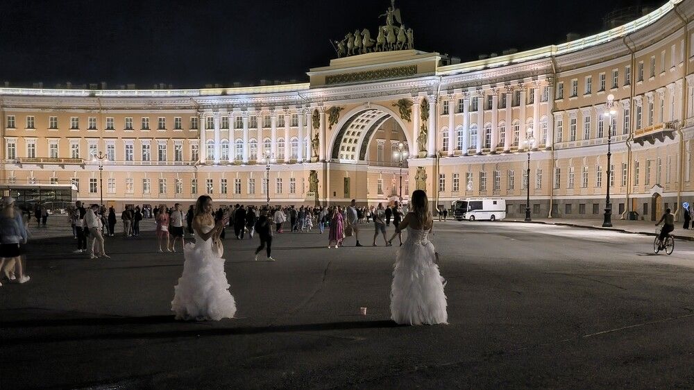 Две девушки в белых свадебных платьях на Дворцовой площади в Санкт-Петербурге