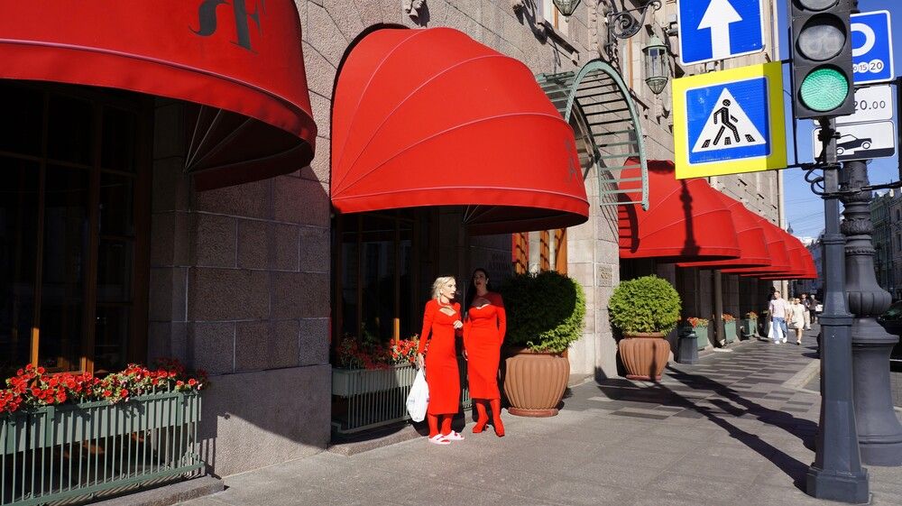 Две женщины на улице возле гостиницы «Астория» в Санкт-Петербурге с красными навесами и маркизами