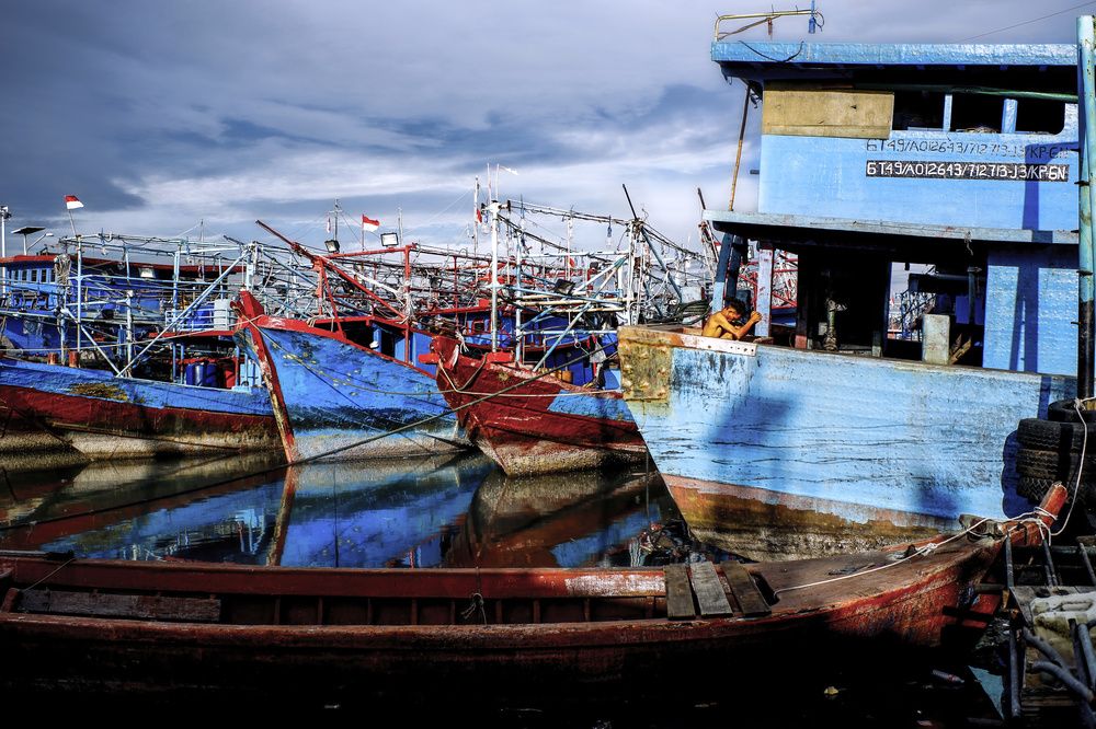 A fisherman is sunbathing on a boat