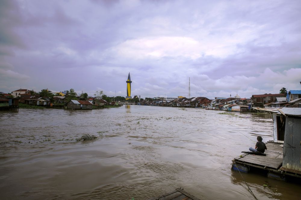 A man is fishing on the banks of the Martapura River
