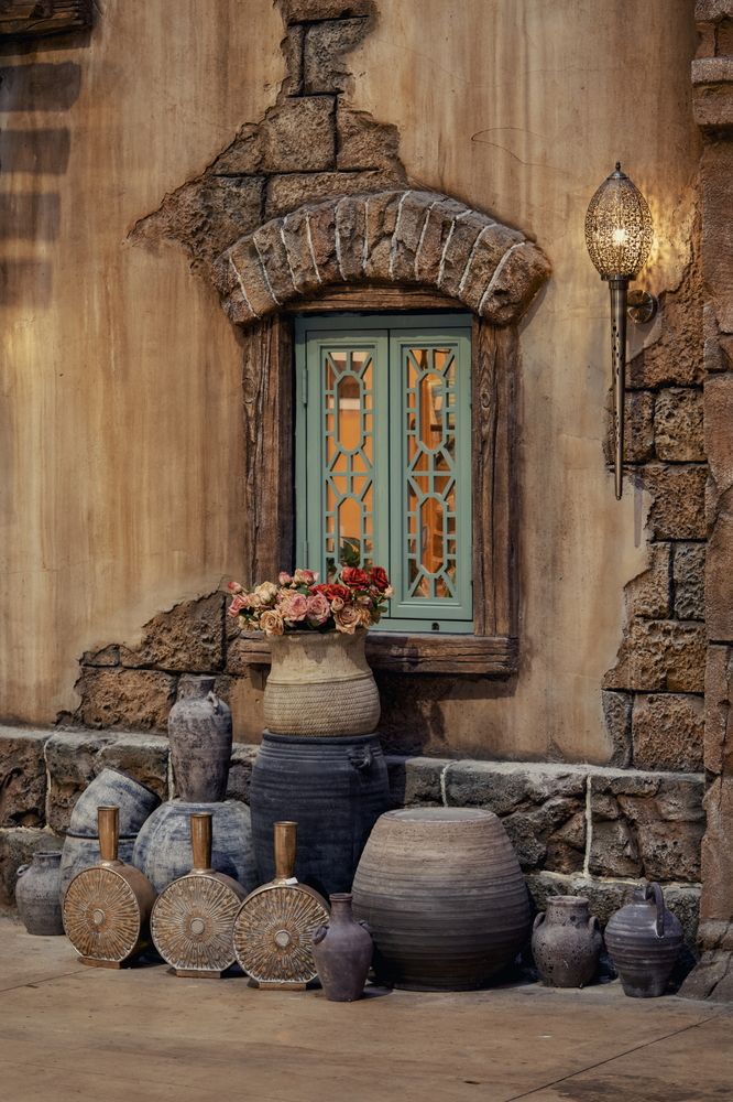 A sturdy stone wall featuring a window alongside an array of vases