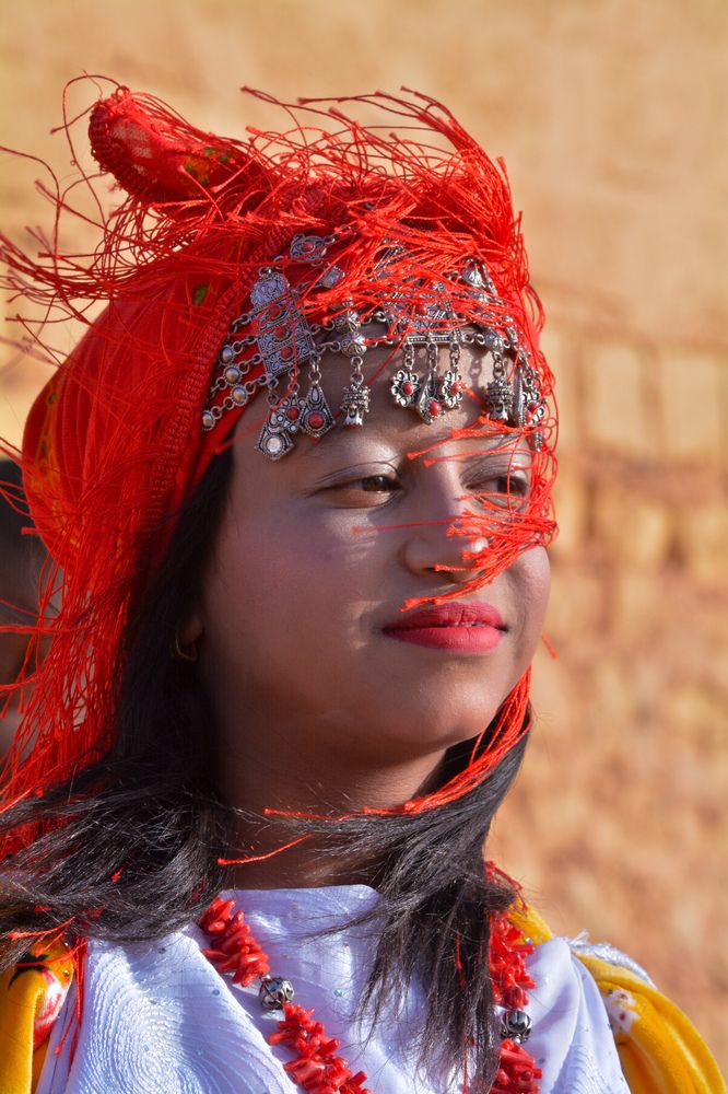 ): Traditional Saharan Dress for a Young Girl): A beautiful young girl dressed in a traditional Saharan outfit, featuring vibrant embroidery and rich cultural details, captured in natural daylight against a serene desert backdrop. This image highlights th