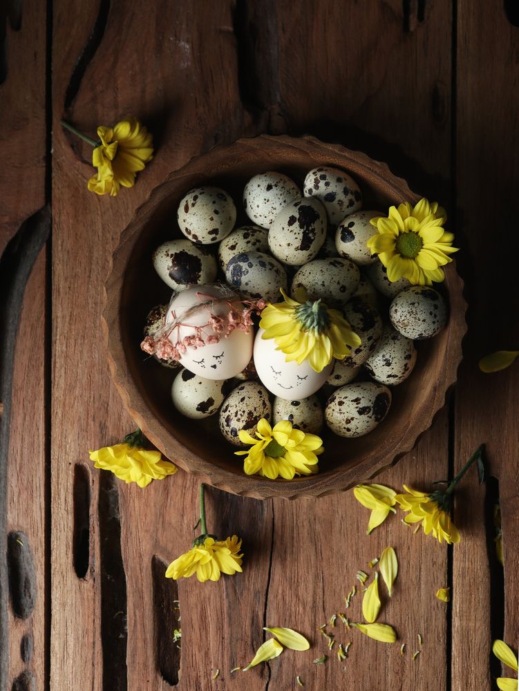 Quail eggs and daisies in a wooden bowl