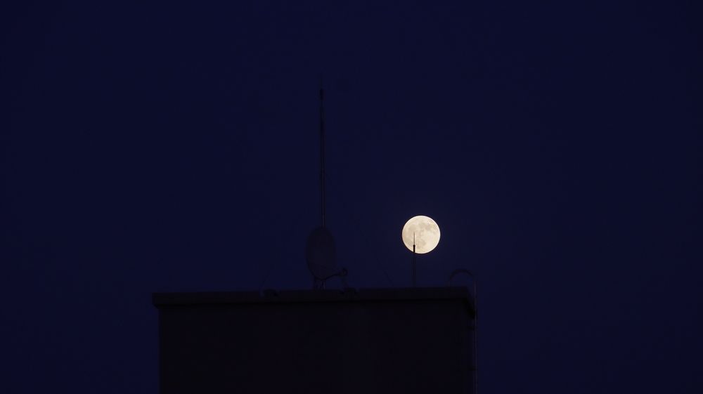 القمر خلف السطح، الهوائي يقطع الصورة. تأطير بسيط، تباين ضعيف. شكرًا للمشاركة. *الضوء خافت. التركيب ثابت.*