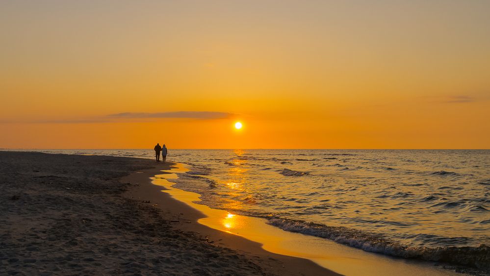 A walk on the beach towards the sun.