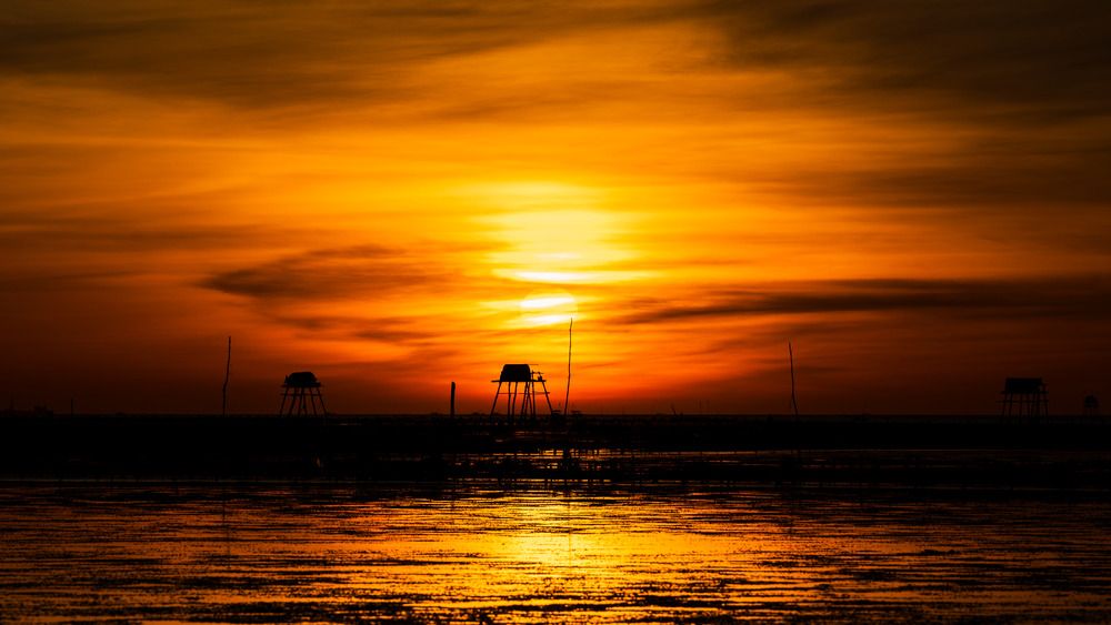 The sun dips below the horizon, bathing the sky in a spectacular wash of orange and gold
