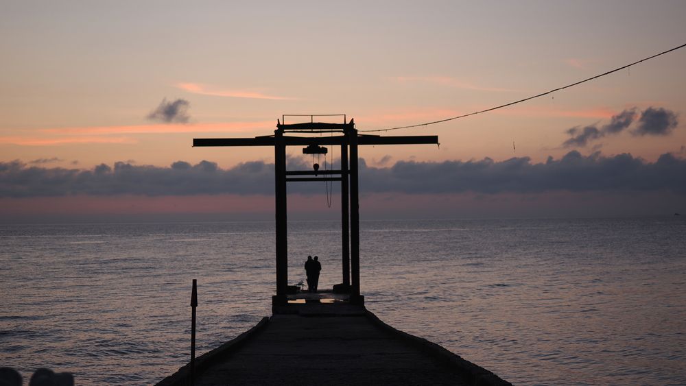 Силуэты закат на море пирс