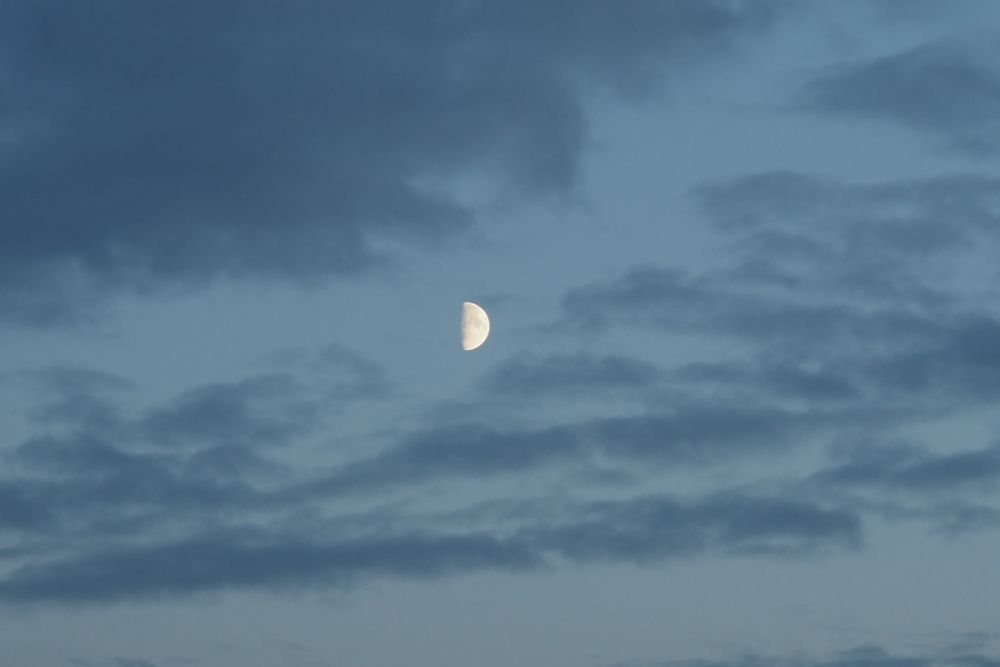 Moon in the blue sky with clouds background.