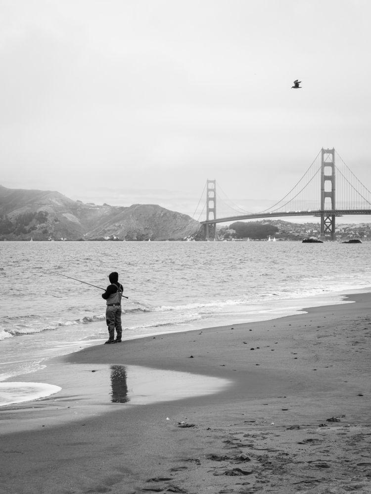 Fisherman on Baker Beach with the Golden Gate Bridge in the background