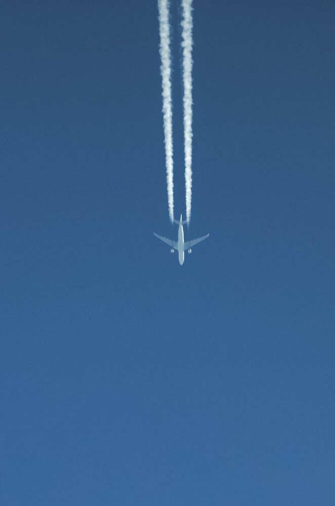 A passenger plane high in the sky with a contrail