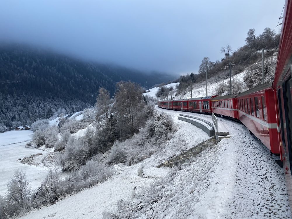The red train travels through the Swiss Alps in winter