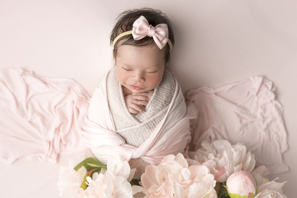 Newborn baby girl surrounded by flowers