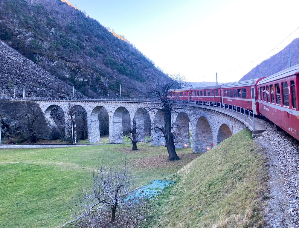 The Bernina Express train passes over a picturesque viaduct in the Swiss Alps