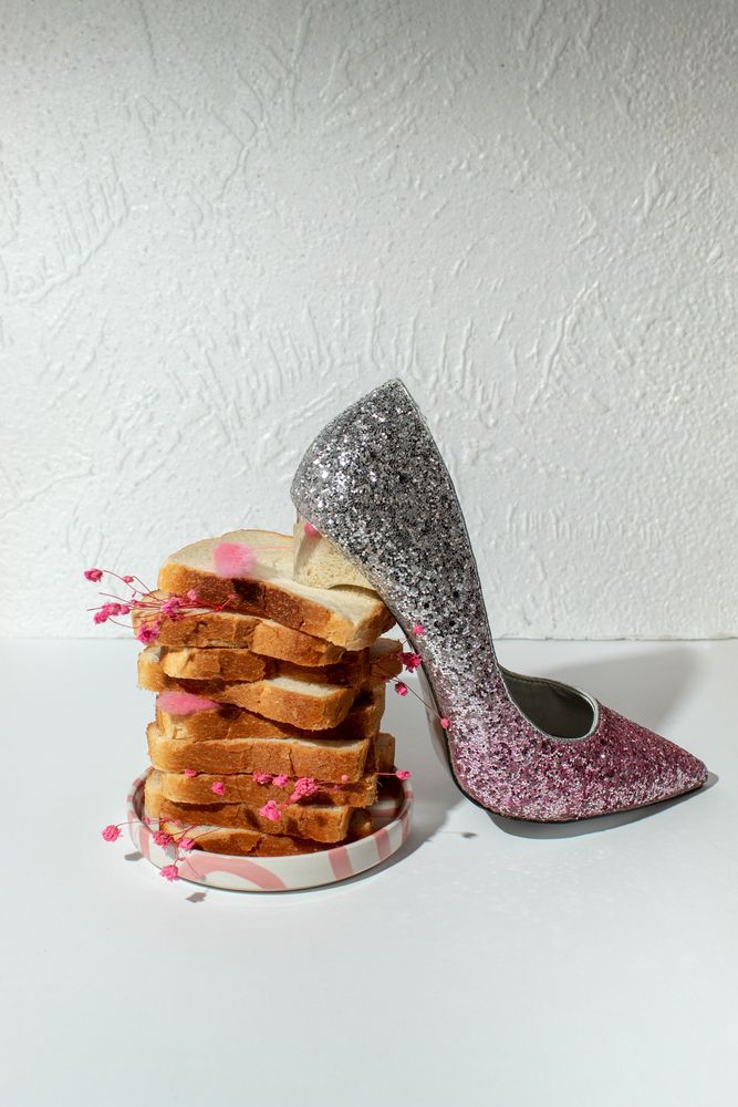 Pink glitter high heel shoe with stacked bread slices, surreal fashion still life concept