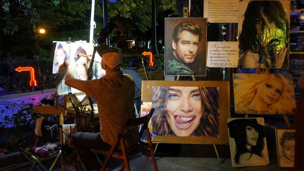 Уличный художник, работающий над портретом