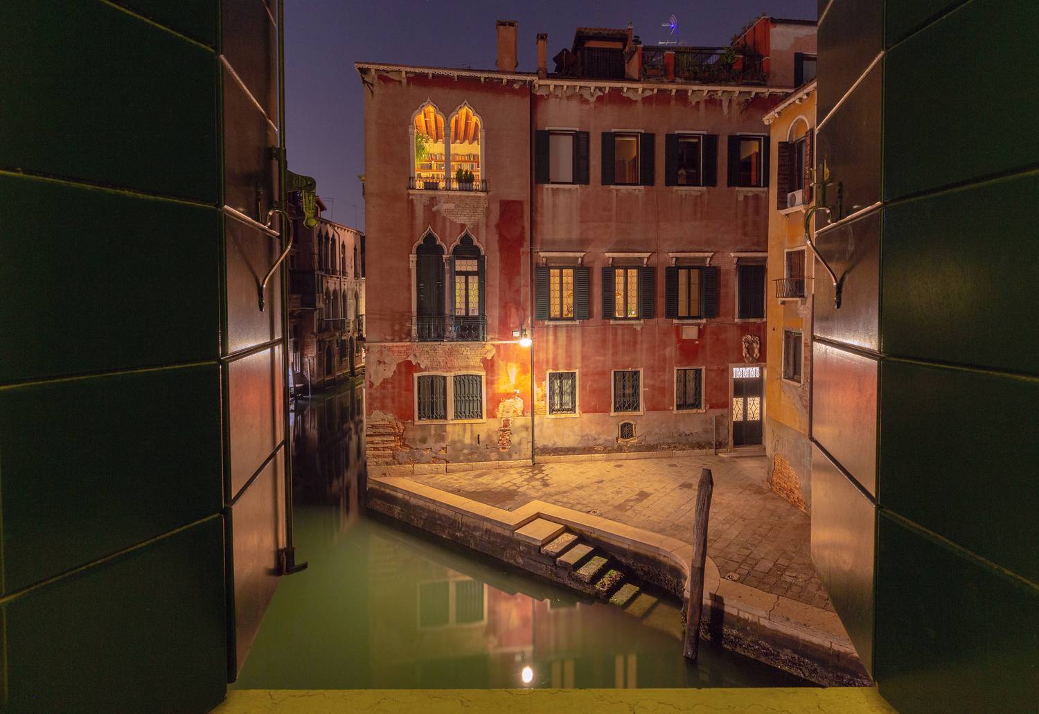 View of a Venetian canal through a window at night.