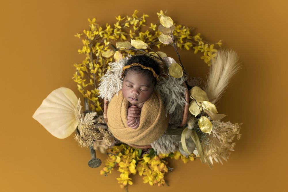 Newborn girl surrounded by yellow flowers