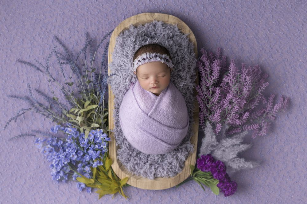 Newborn girl with purple flowers