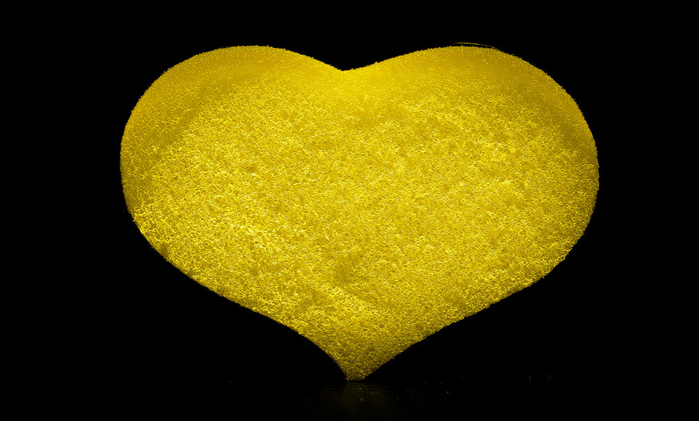 Yellow foam sponge for a heart-shaped shower on a black background.