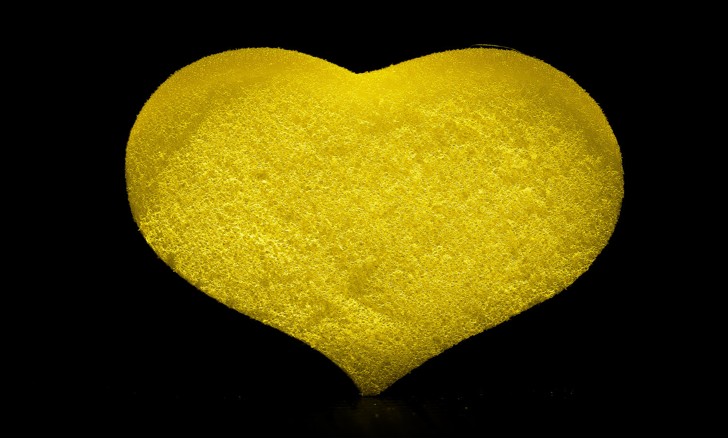 Yellow foam sponge for a heart-shaped shower on a black background.