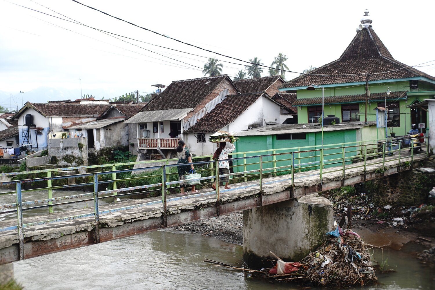 Residents Crossing a Village Bridge over a River